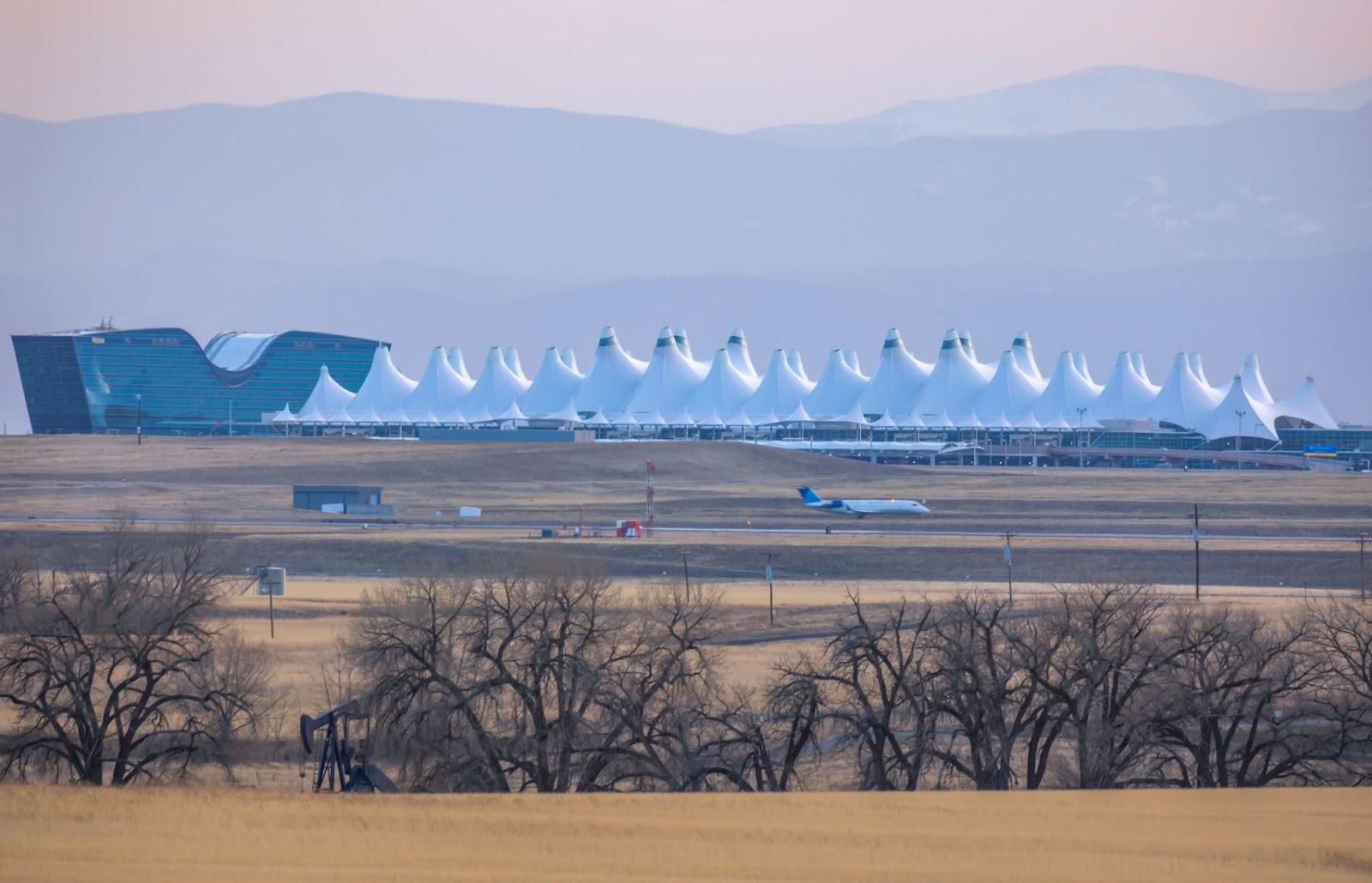 The Denver International Airport against a silhouette of Rocky Mountains.