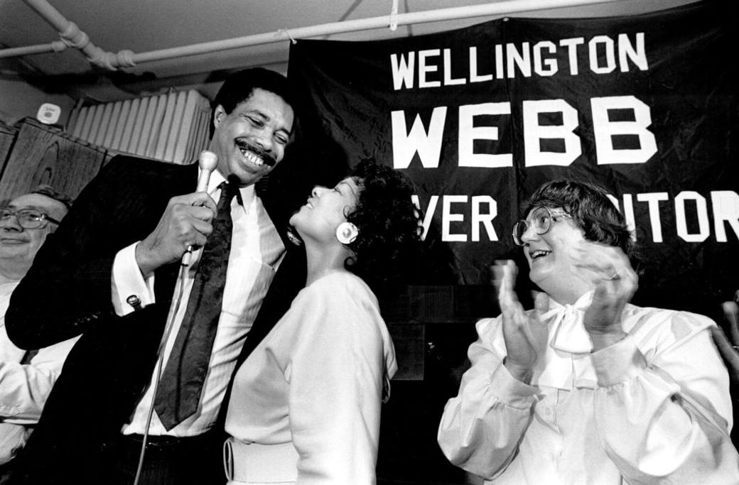 Candidate and partner embrace after a win while onlookers cheer
