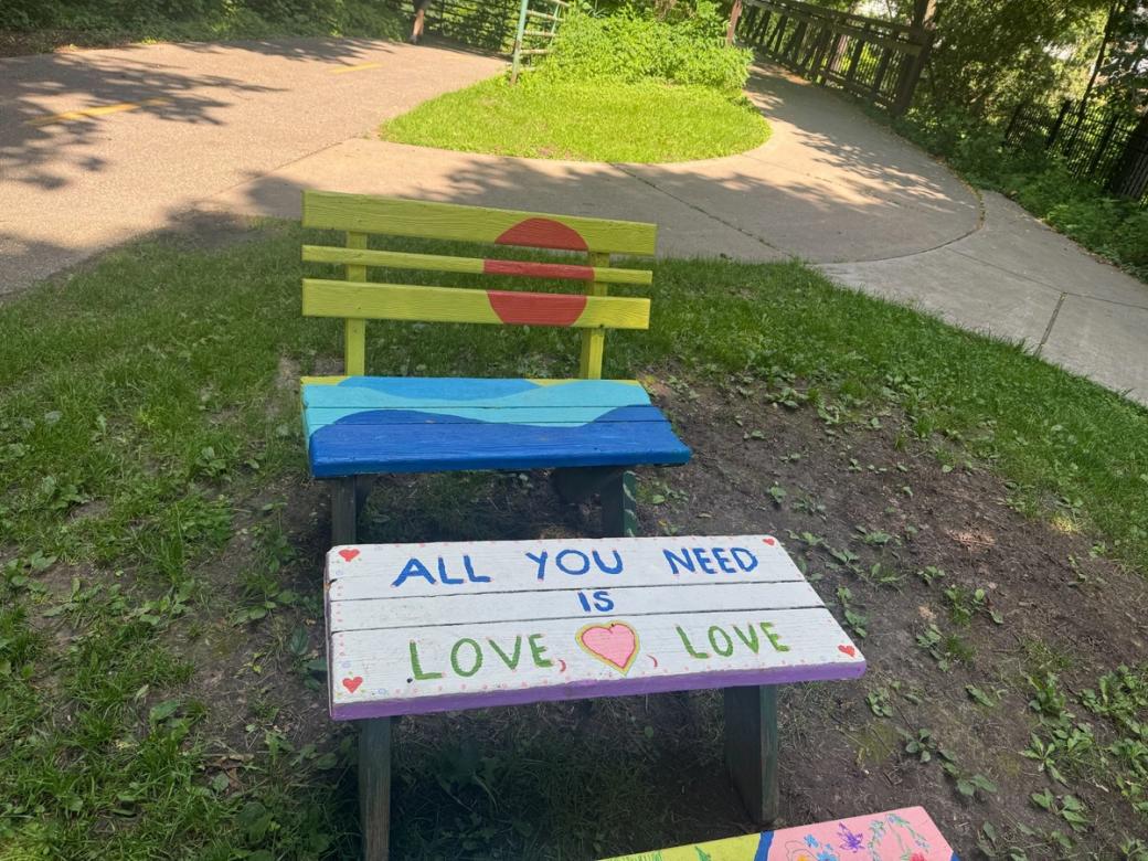 A green and blue bench sits behind a white painted table that reads "All You Need is Love Love."