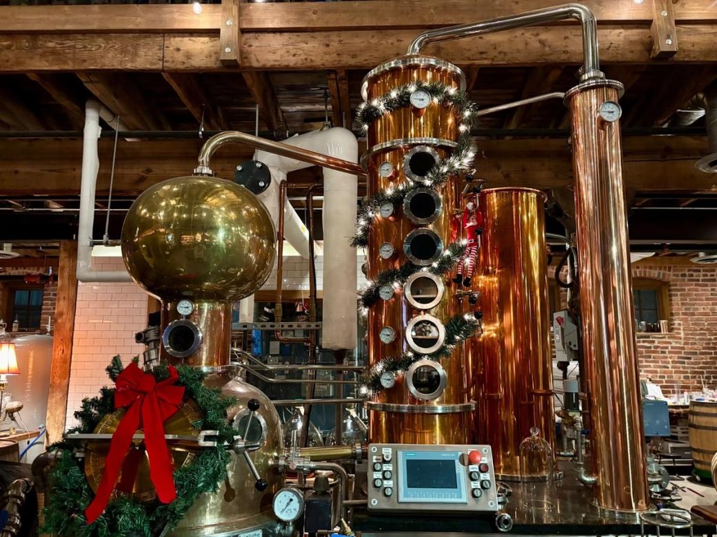 Copper distillation equipment wrapped in holiday decorations.