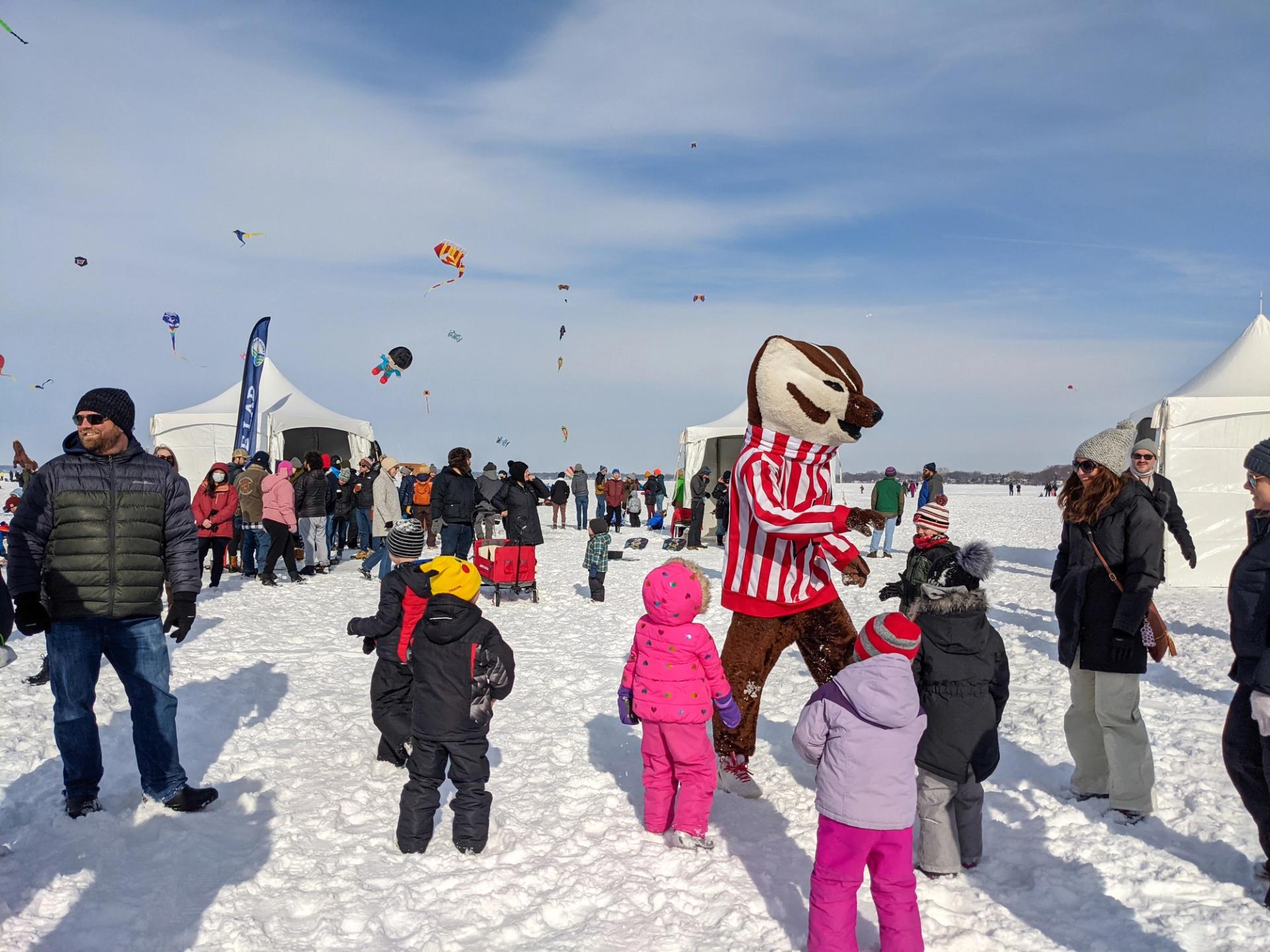 A group of people including a person in a badger costume on snow.