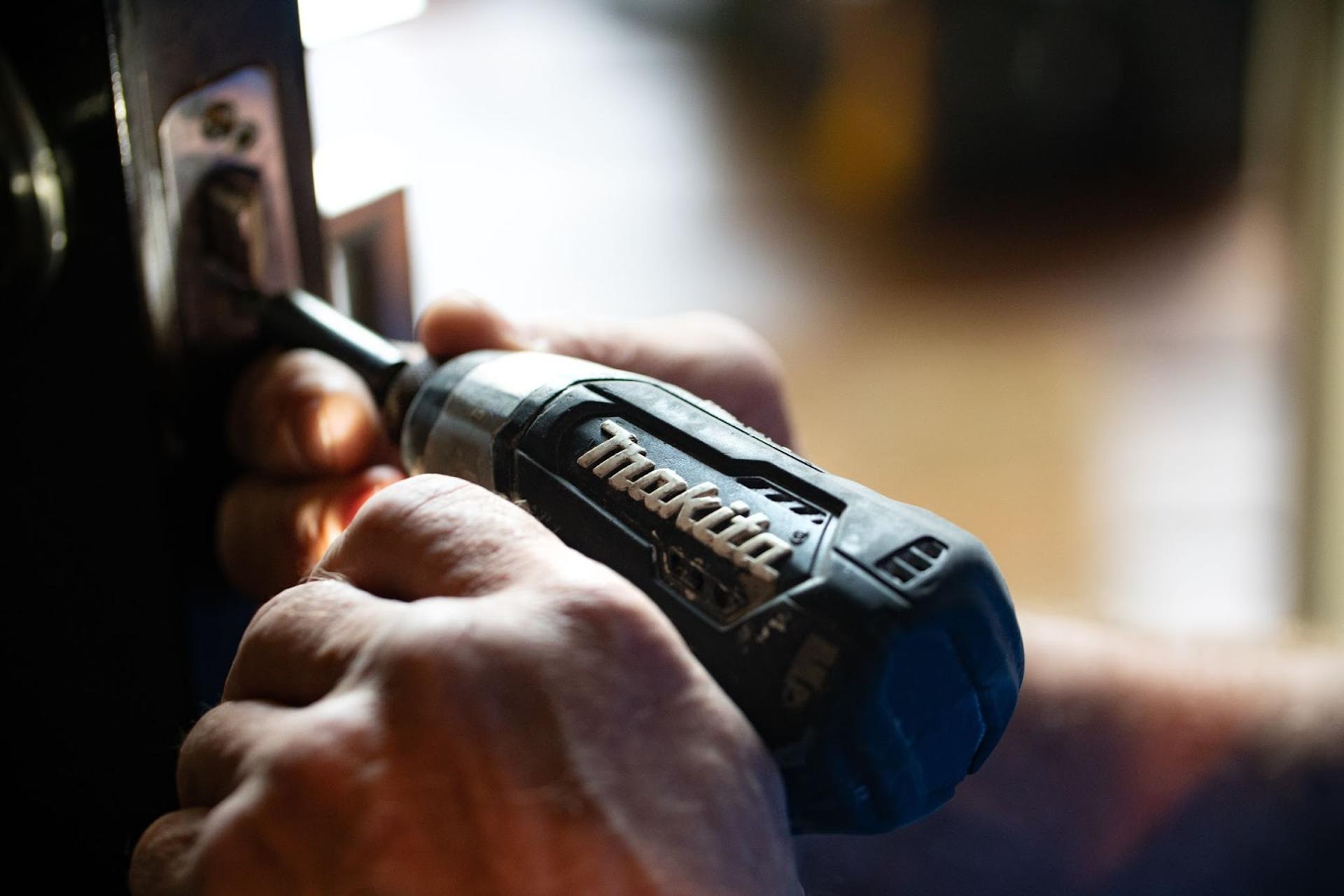 Hands holding a Makita brand power tool.