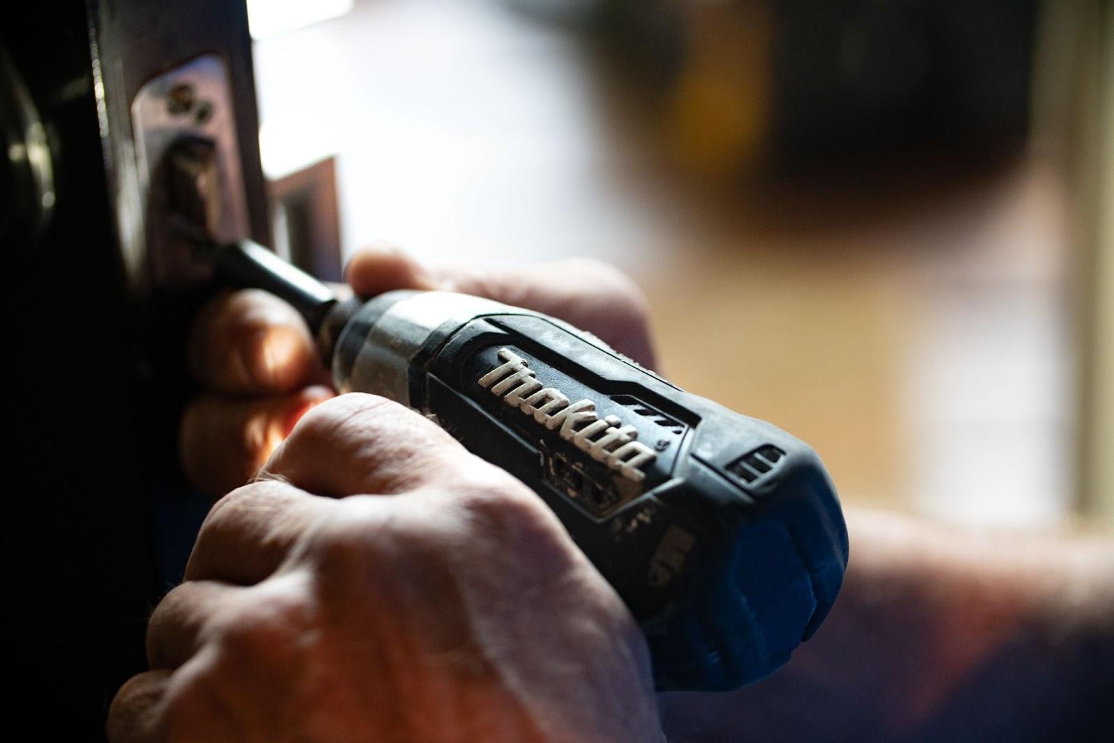 Hands holding a Makita brand power tool.