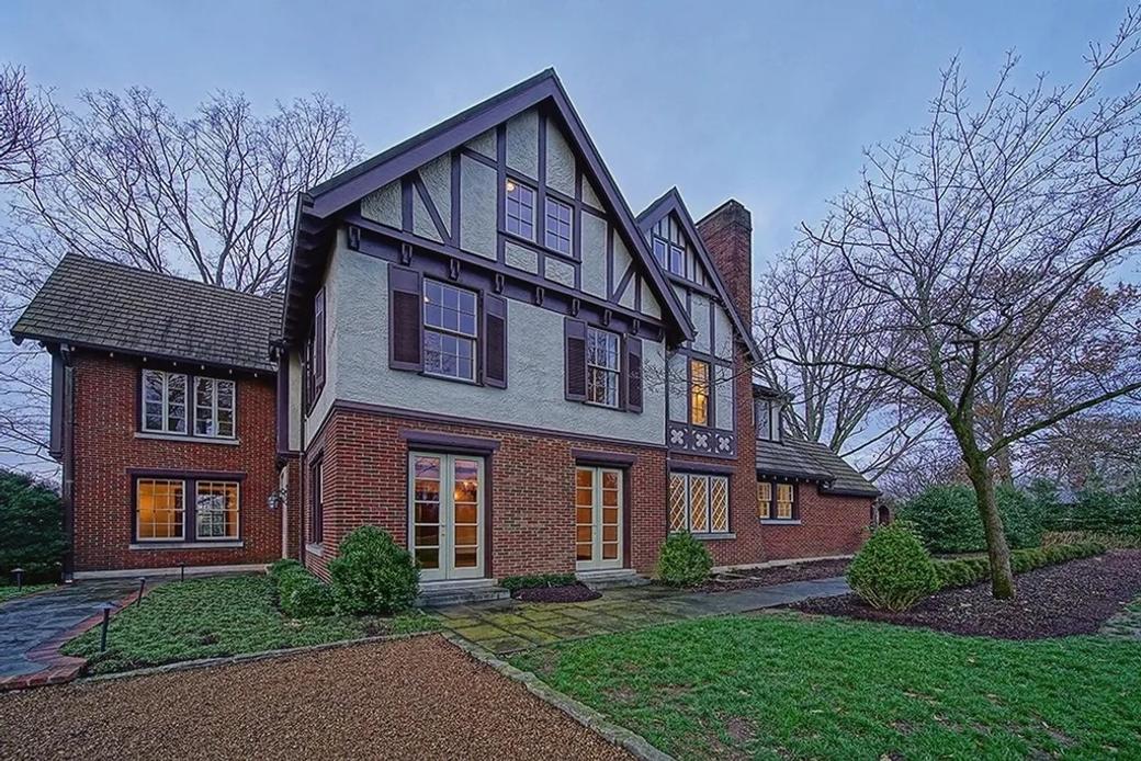 A large Tudor-style home with red brick and white stucco.