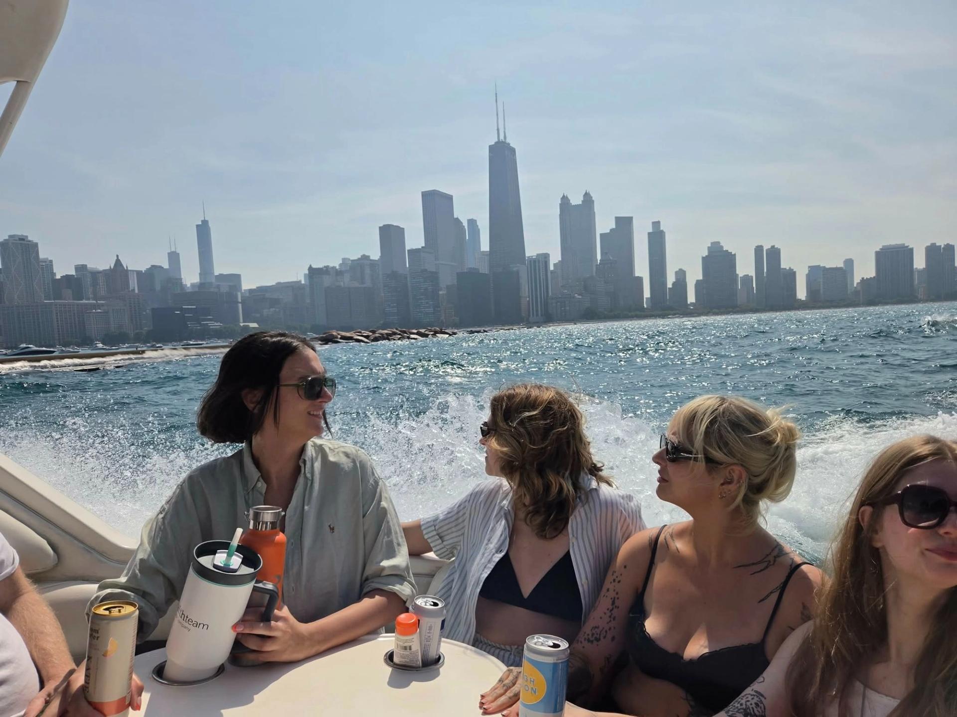 Four women siting at a table on a boat with the chicago skyline in the background