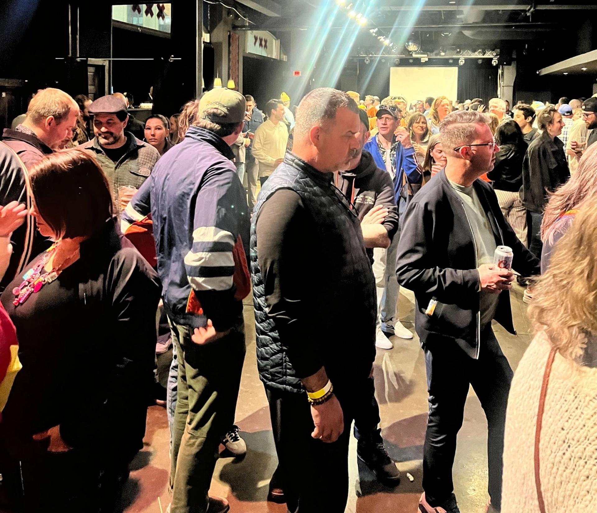 A crowd of people standing in a bar