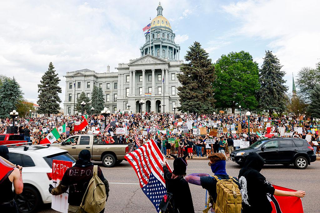 Groups of people gather to protest waving flags in front of government building