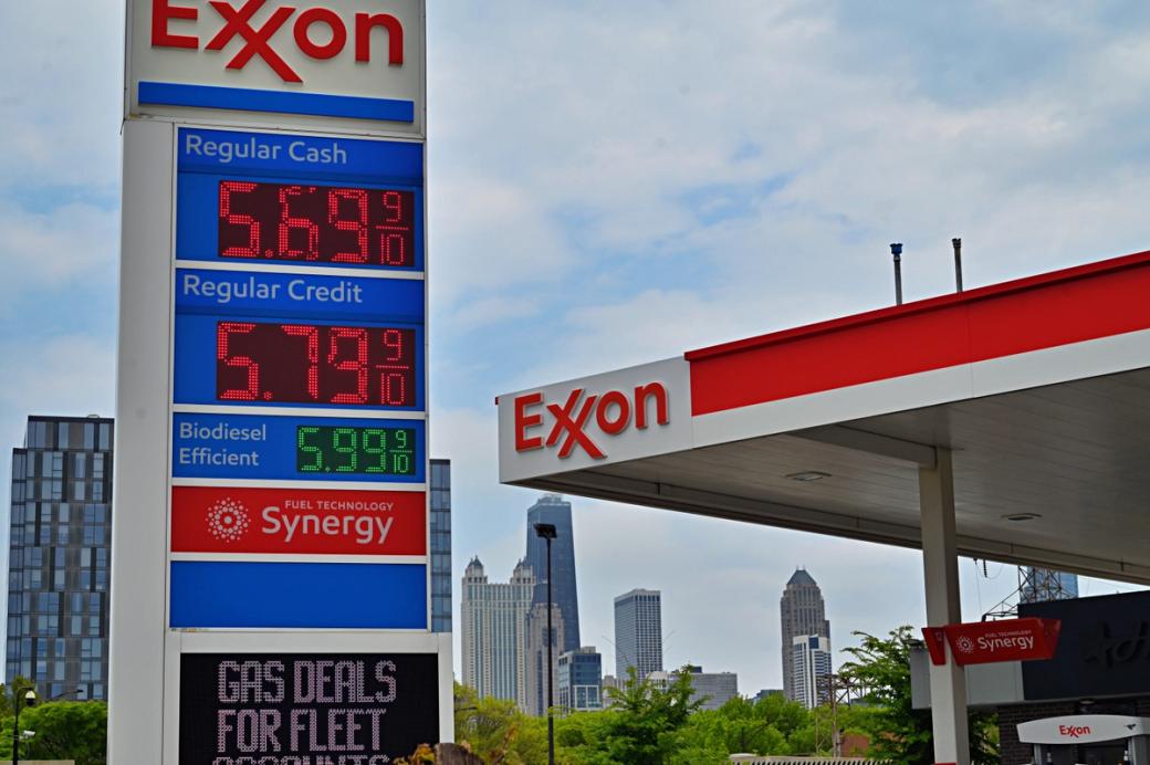 A pedestrian view of an Exon station where the gas prices read 5.69 and 5.79