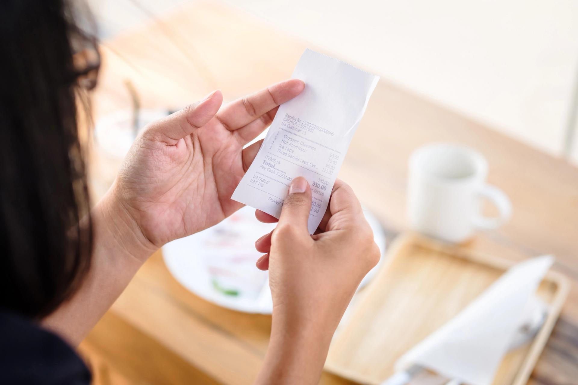 A person checks their receipt after a meal in a restaurant.