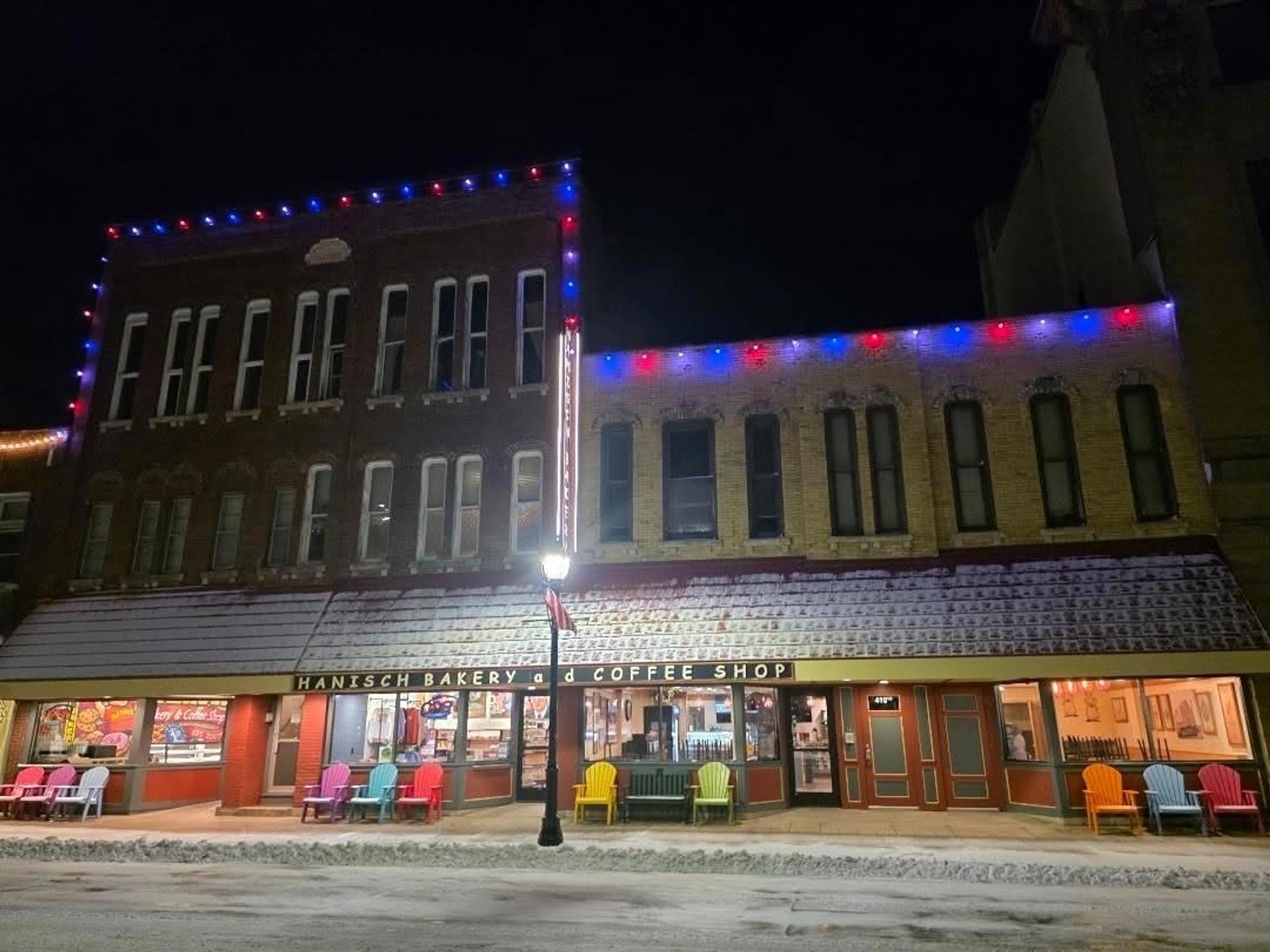 A pedestrian perspective of Hanisch Bakery and Coffee. The left side is taller than the right side. There are Christmas lights on the building as well