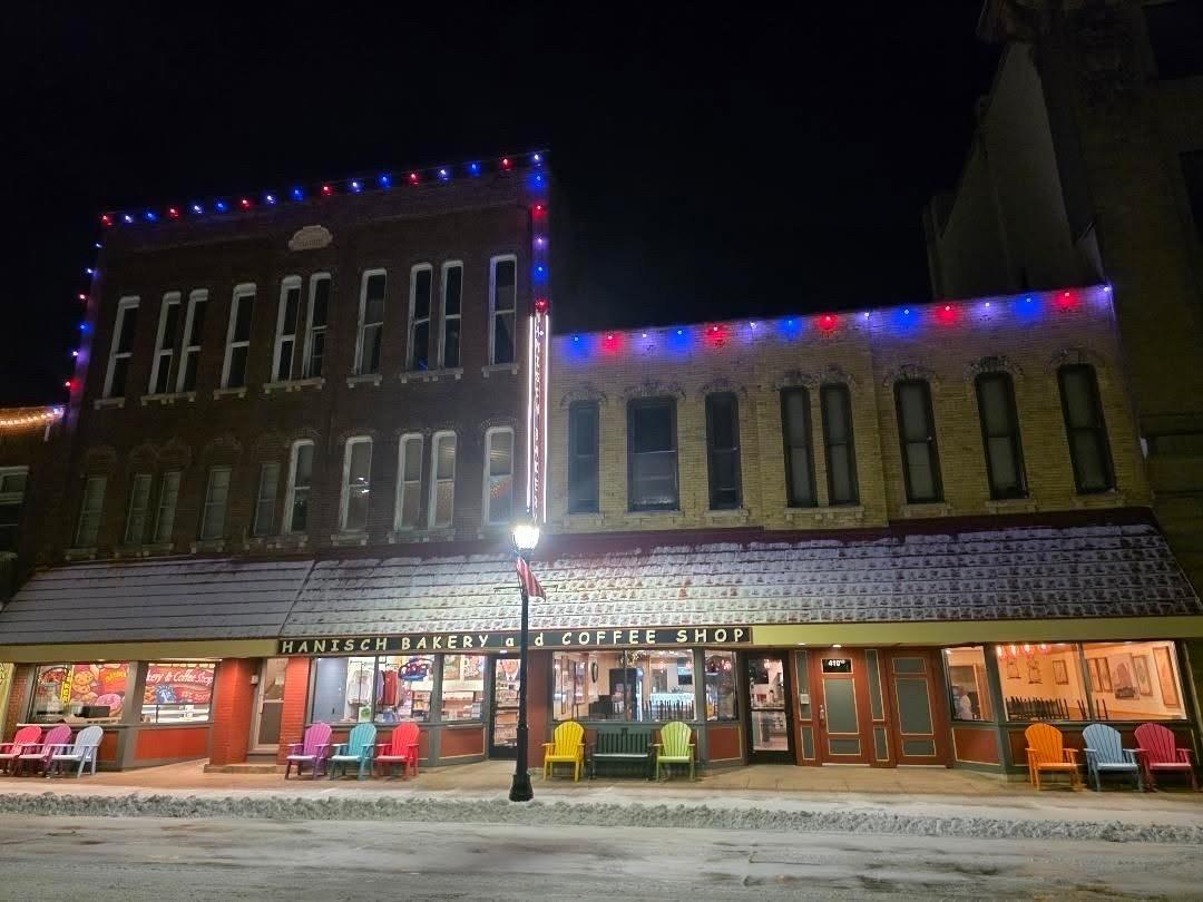 A pedestrian perspective of Hanisch Bakery and Coffee. The left side is taller than the right side. There are Christmas lights on the building as well