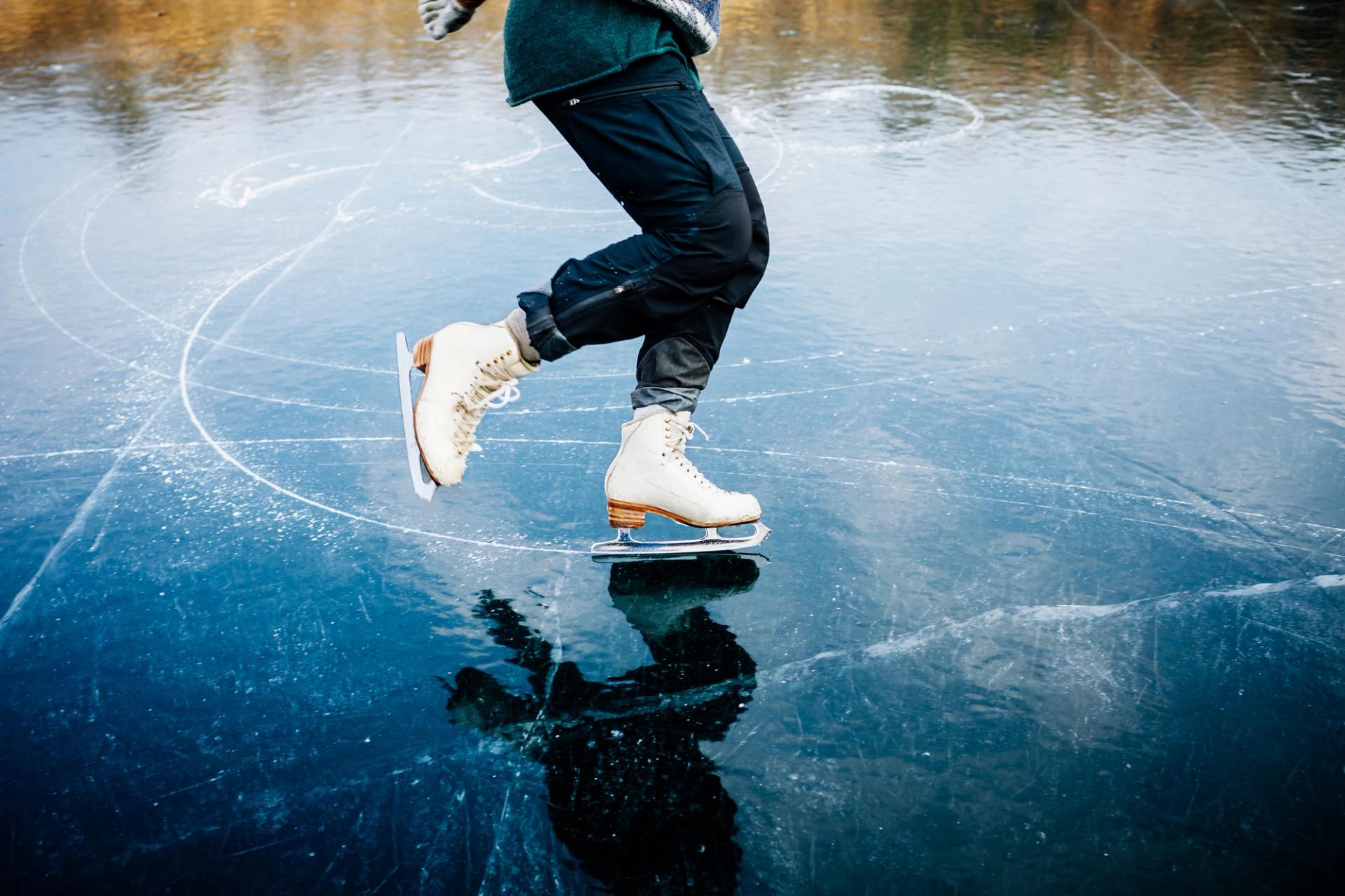 An semi professional ice skater's blades cutting curves and spirals into a frozen lake.