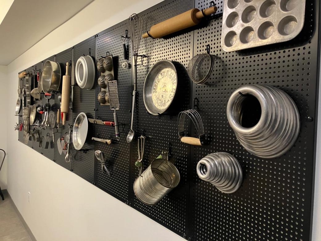 A black wall covered with kitchen tools.