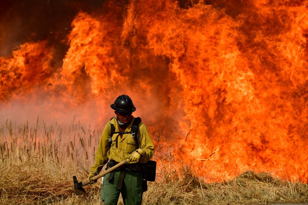 Denver firefighter stands with large blaze in the background