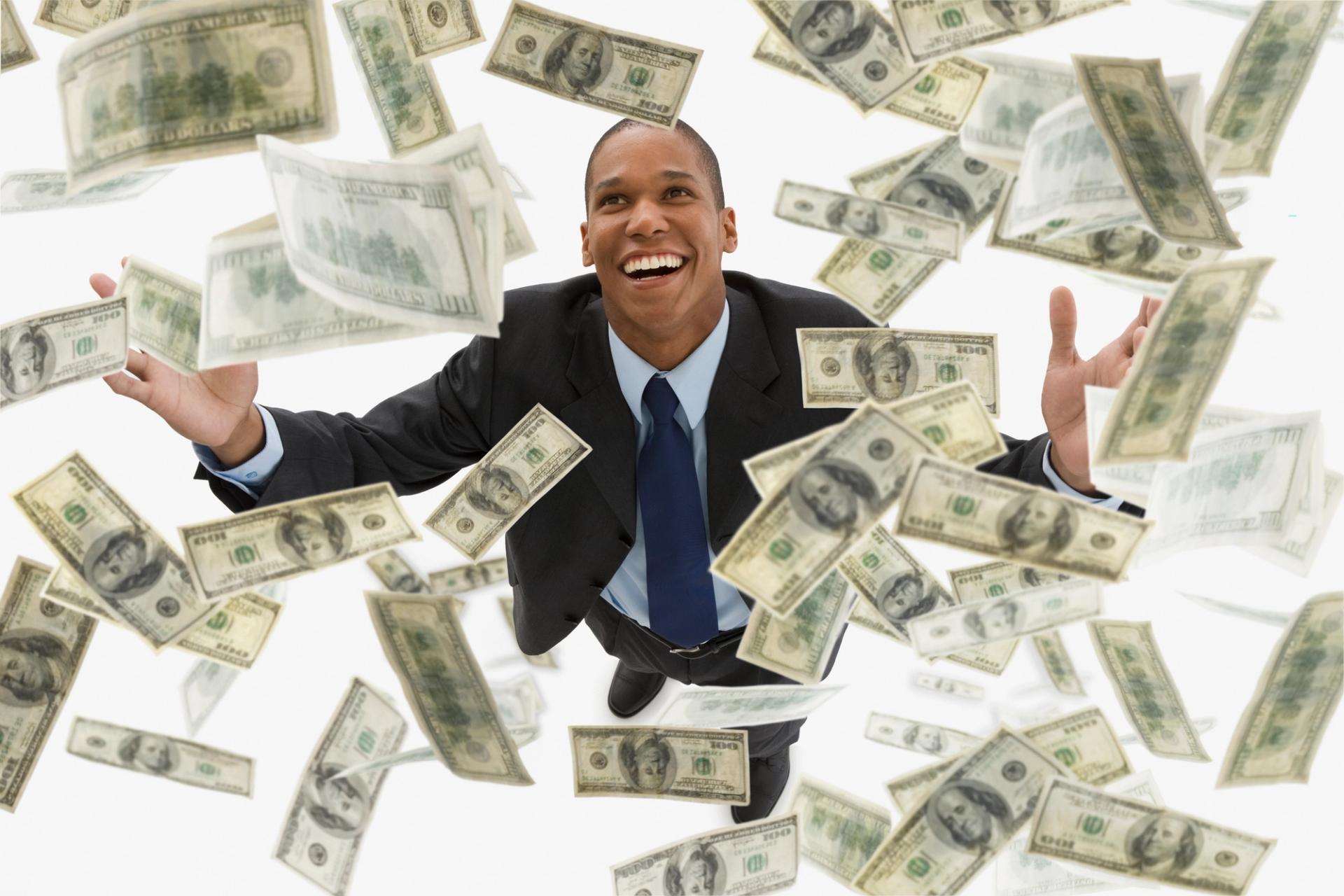 Photo of man with money swirling around him.