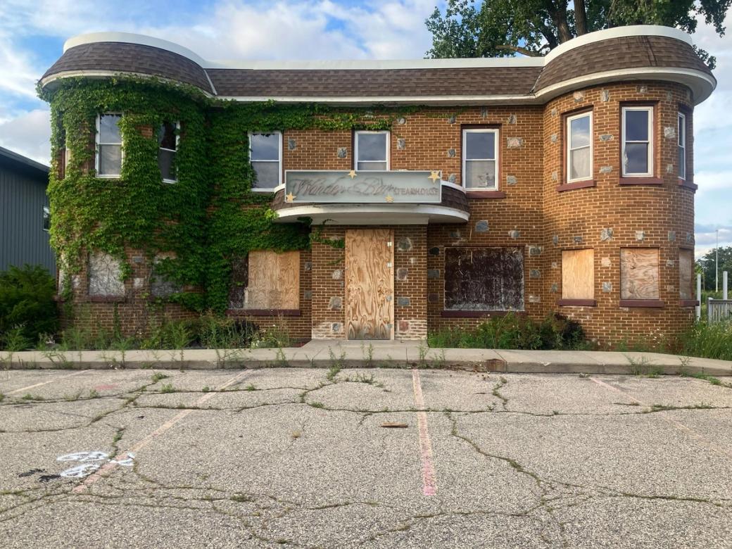 A two-story brick building with boarded up windows and ivy growing up the side was the location of Wonder Bar Steakhouse. It now sits abandoned. 