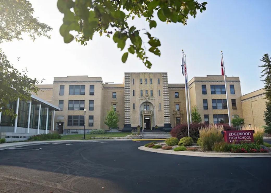 The front of Edgewood High School - a beige building with two flag poles out front and a red sign reading "Edgewood High School."