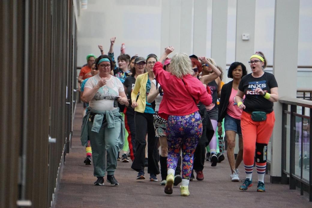 A crowd in spandex and bright collars walk the empty corridor of Lloyd Center.