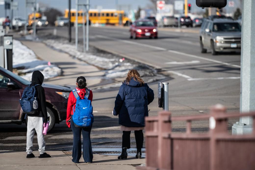 Three people standing at a crosswalk