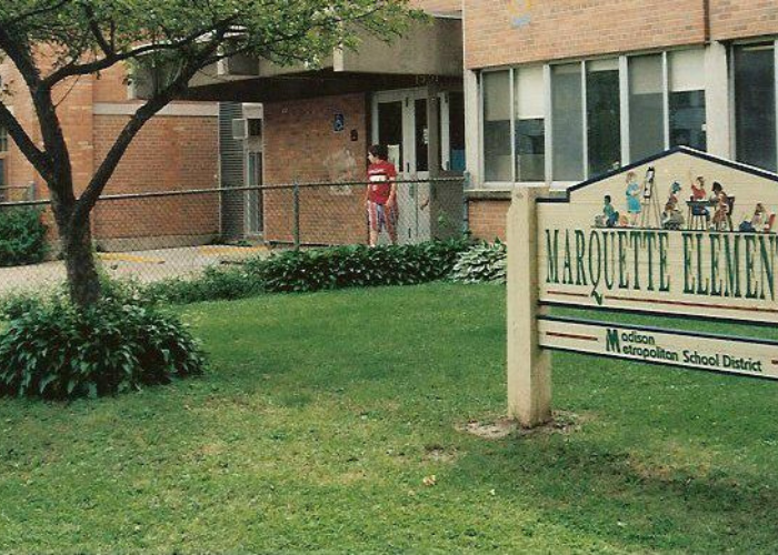 A child in a red shirt leaving a school.
