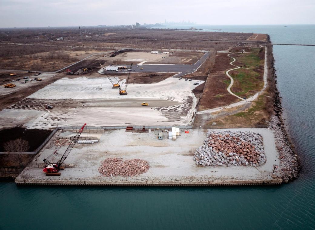An overhead shot of a large plot of land with a crane and a large pile of stone