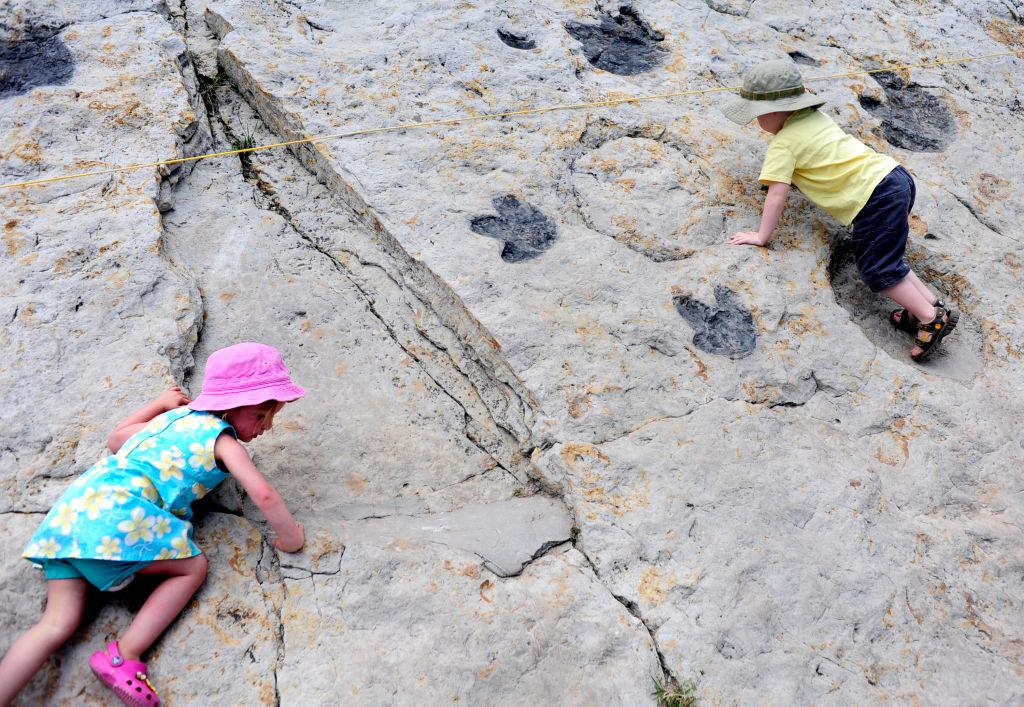 Children climb in real dinosaur footprints at Dinosaur Ridge in Morrison.