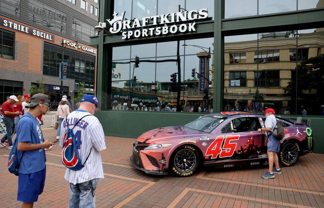 People check out a Michael Jordan-themed Bubba Wallace race car parked outside DraftKings Sportsbook and Wrigley Field.