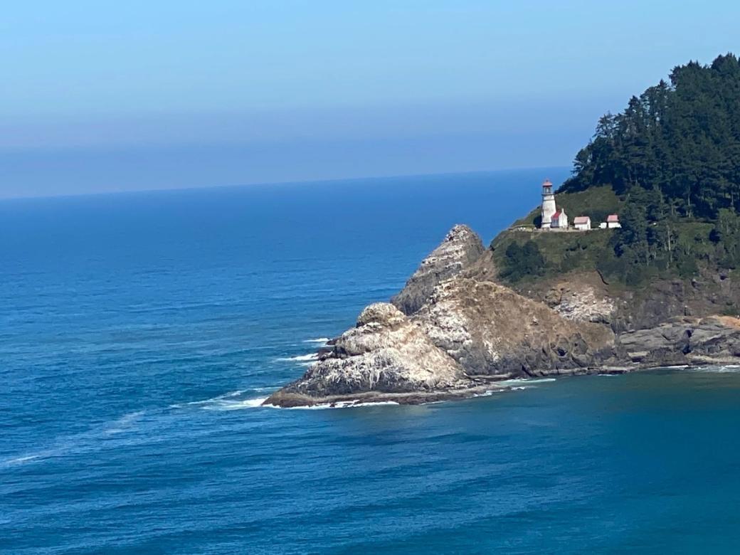Lighthouse on a rocky promontory surrounded by blue. 
