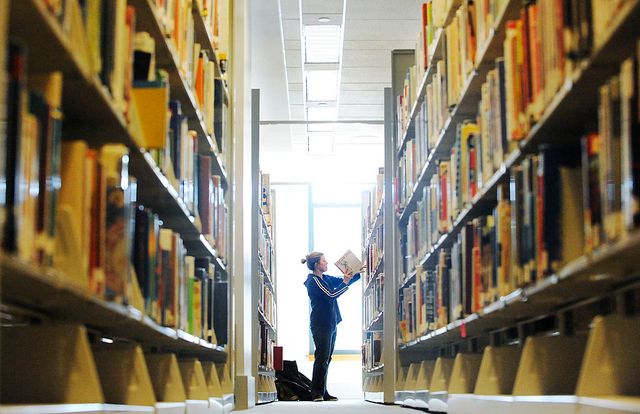 a person peruses the bookshelves of a library
