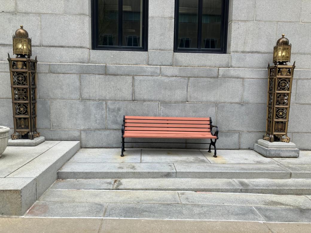 A wooden bench blanked by two bronze lamps.