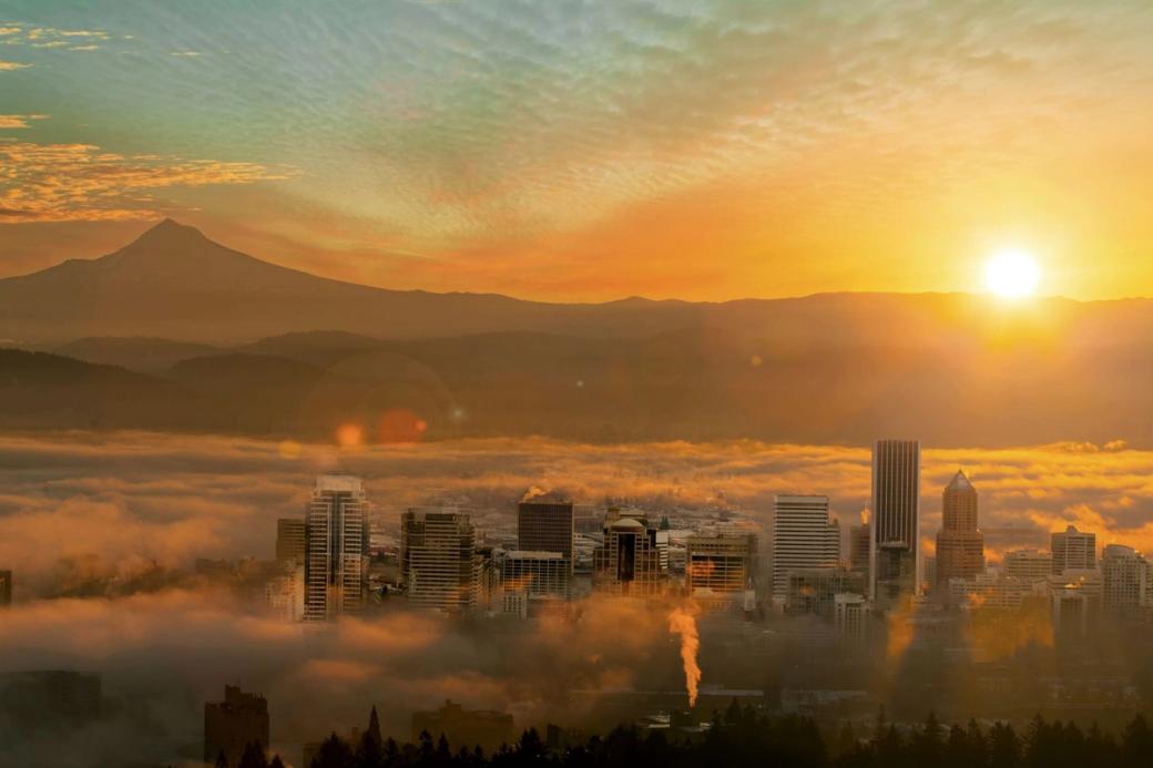 Foggy urban skyline viewed from above at sunrise with mountains in the distance
