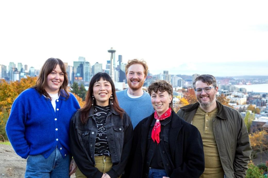An image of the City Cast Seattle team standing in front of a view of Seattle including the Space Needle