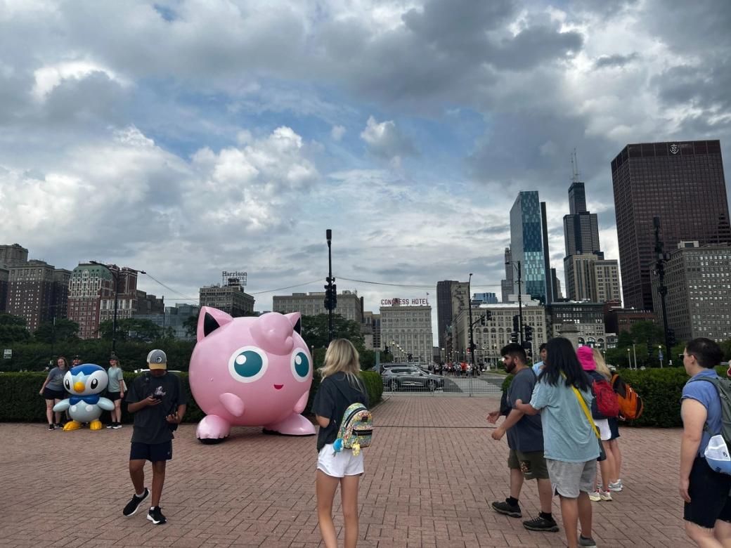 A group of people gathered by an inflatable piplup and jigglypuff