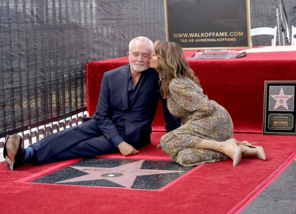 Actor Bradley Whitford sits on a red carpet alongside his star on the Hollywood Walk of Fame.