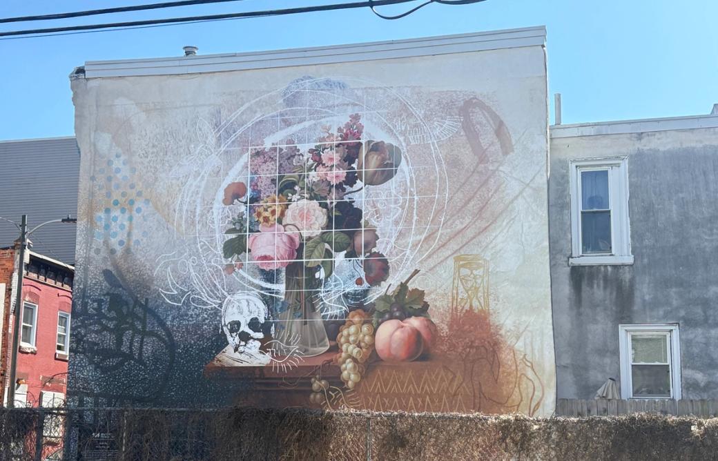 Still life mural of a bouquet of flowers, fruit, and a skull on a table