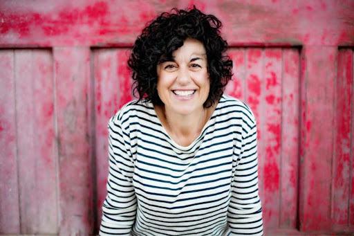 Author Ann Garvin poses in front of a red wall.