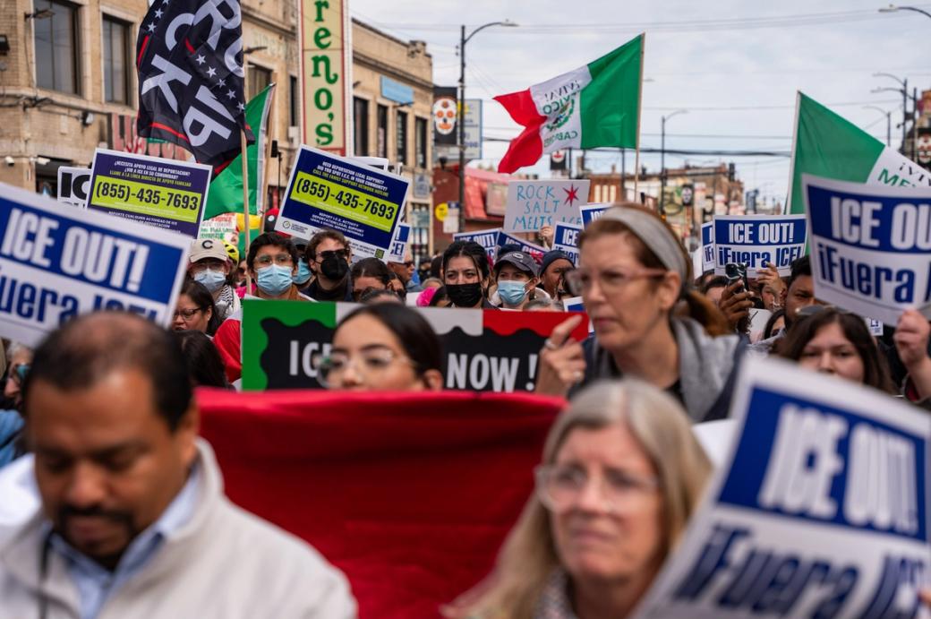 A group of people protesting in the street with signs that say "ICE OUT!"