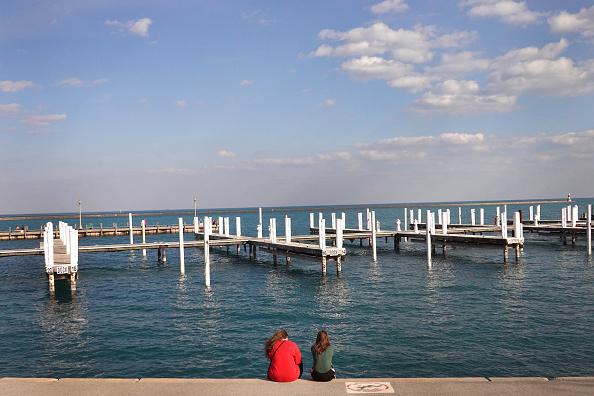 Two people sitting in front of the lakefront in Chicago, Illinois overlooking boat docks.
