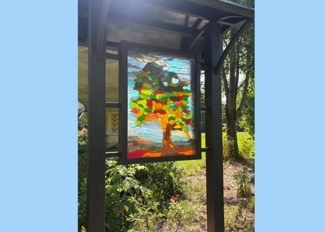 A stained glass image of a tree with red, green and orange colors.