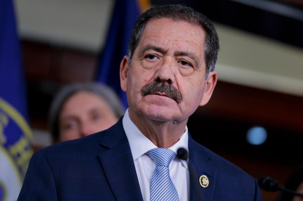 A man in a suit with a mustache looking past the camera