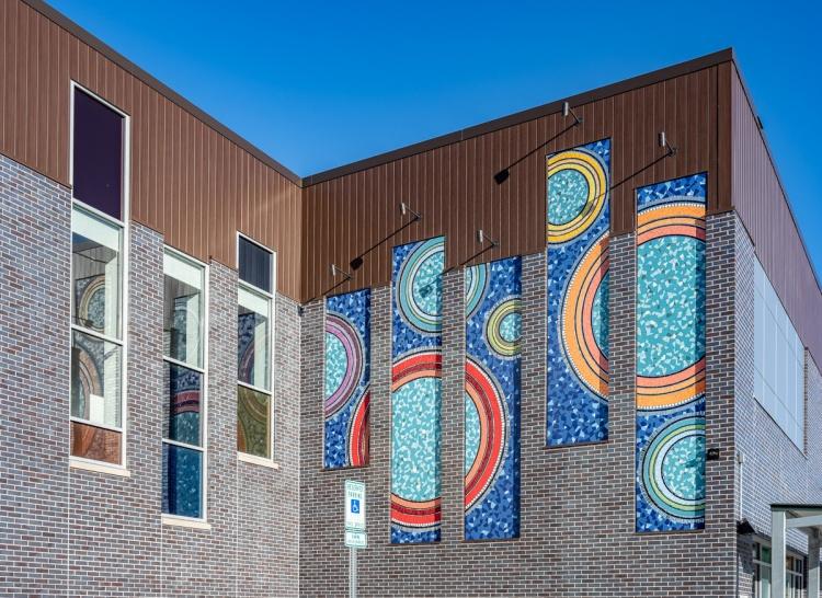 A gray brick building with brightly colored mosaics.