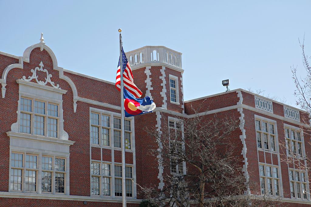 Brick school with flags and a blue sky in the background