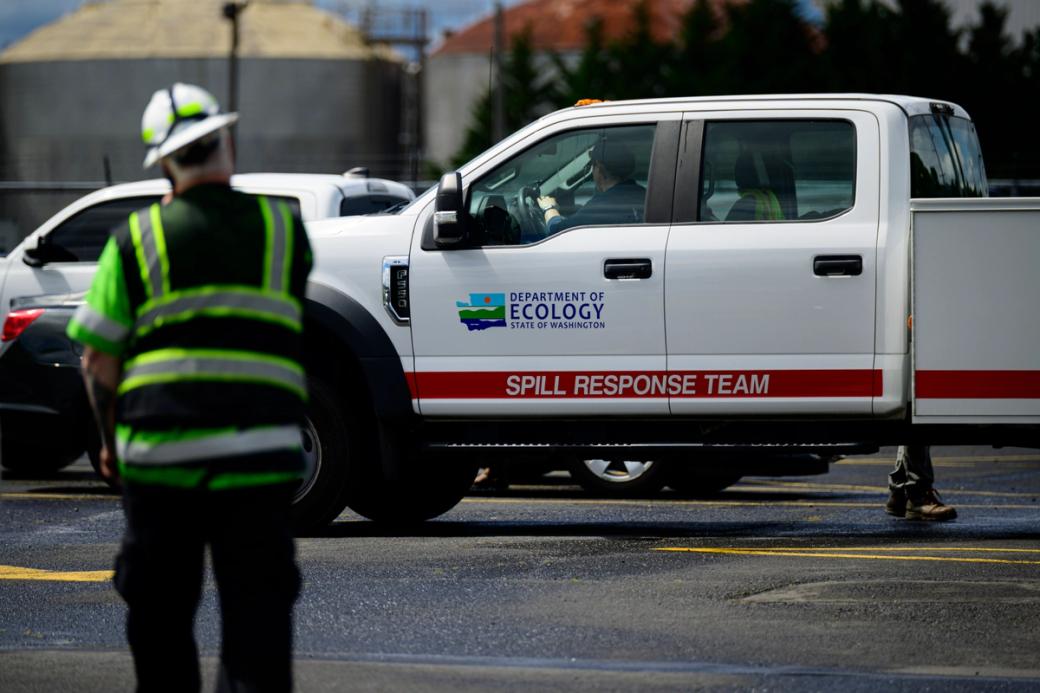 A Washington State Department of Ecology truck is pulling into the scene in front of the Nippon Dynawave Packaging facility following a fatal chemical storage tank implosion. 
