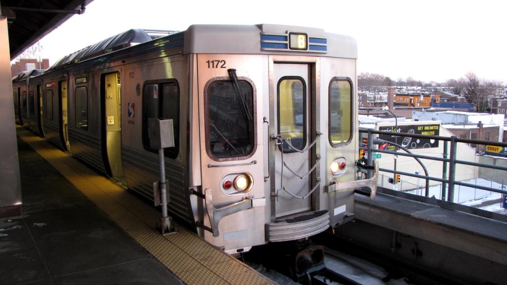 A silver SEPTA Market-Frankford Line train car is parked on an elevated platform. 