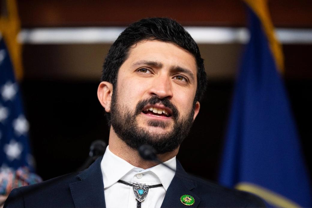 U.S. Representative Greg Casar, dressed in a suit and bolo tie, speaks into microphones.