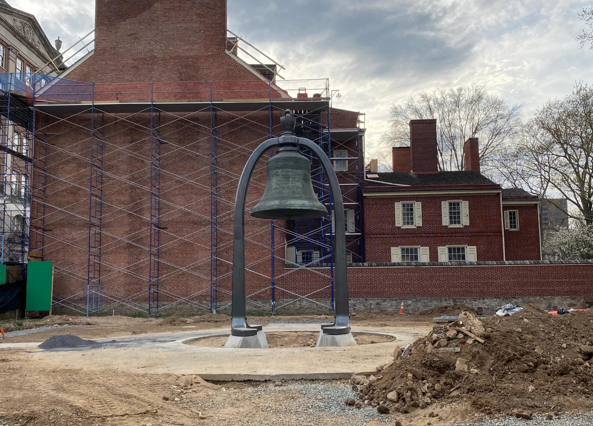 A bell suspended in the air, surrounded by dug-up ground.