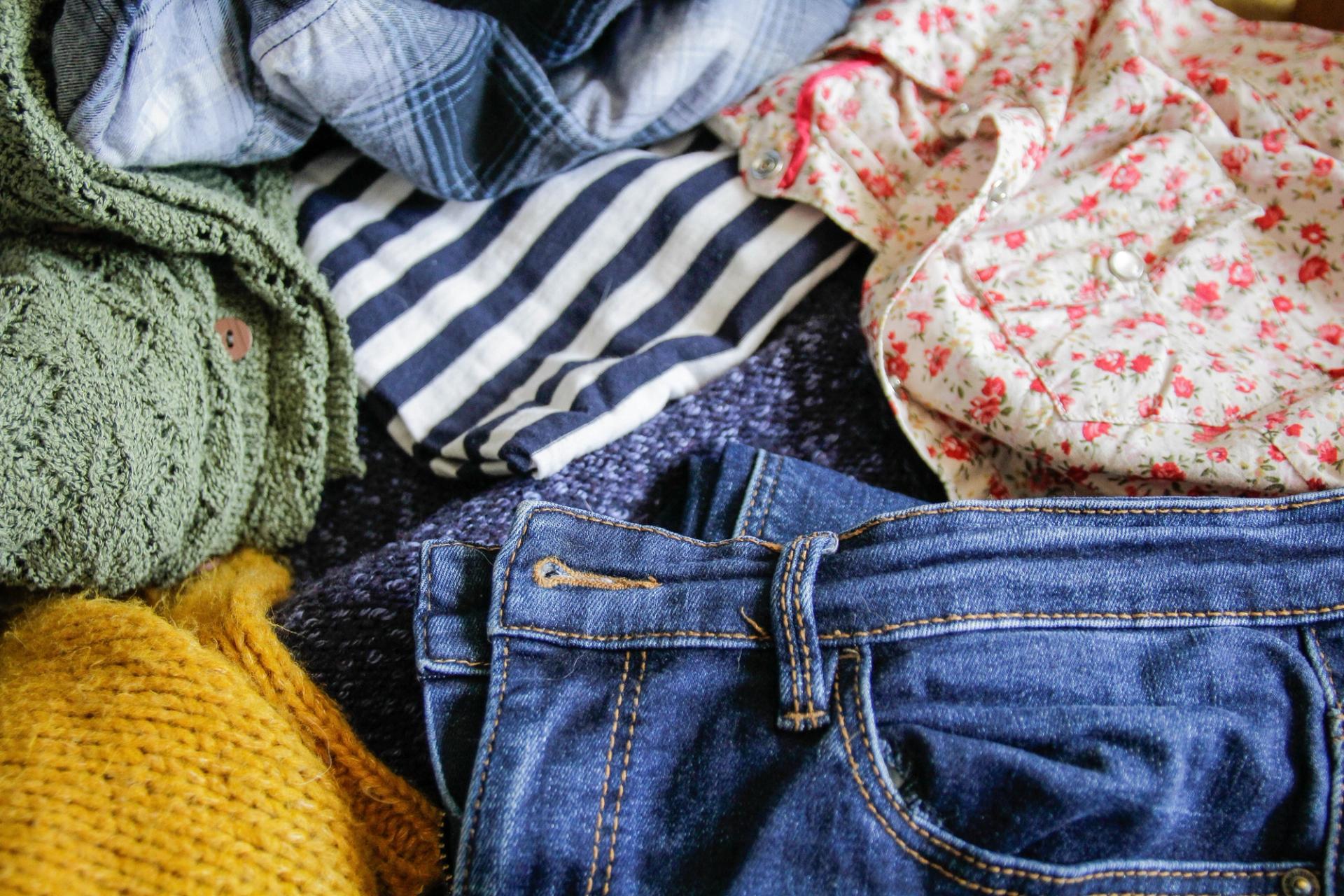 a zoomed in image of clothing -- jeans, t-shirts, and sweaters