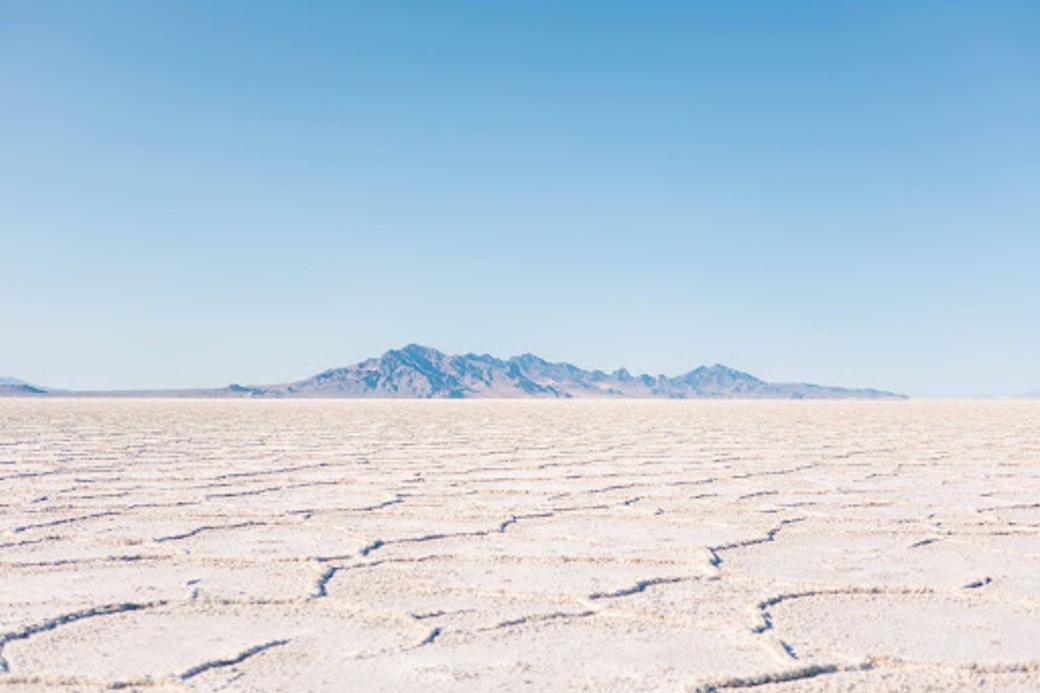 A view of the Bonneville Salt Flats with a clear sky and mountains in the back.