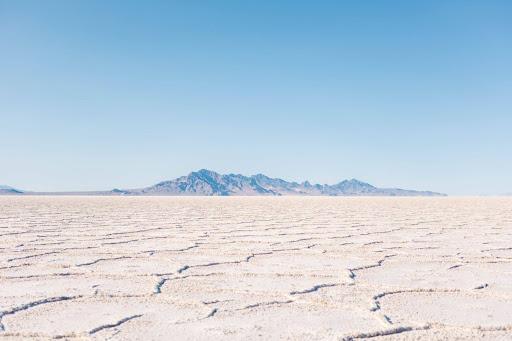 A view of the Bonneville Salt Flats with a clear sky and mountains in the back.