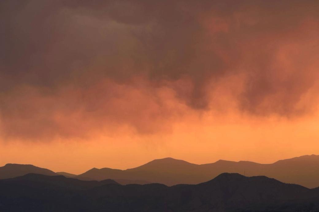 smokey orange sky above dark mountain range.